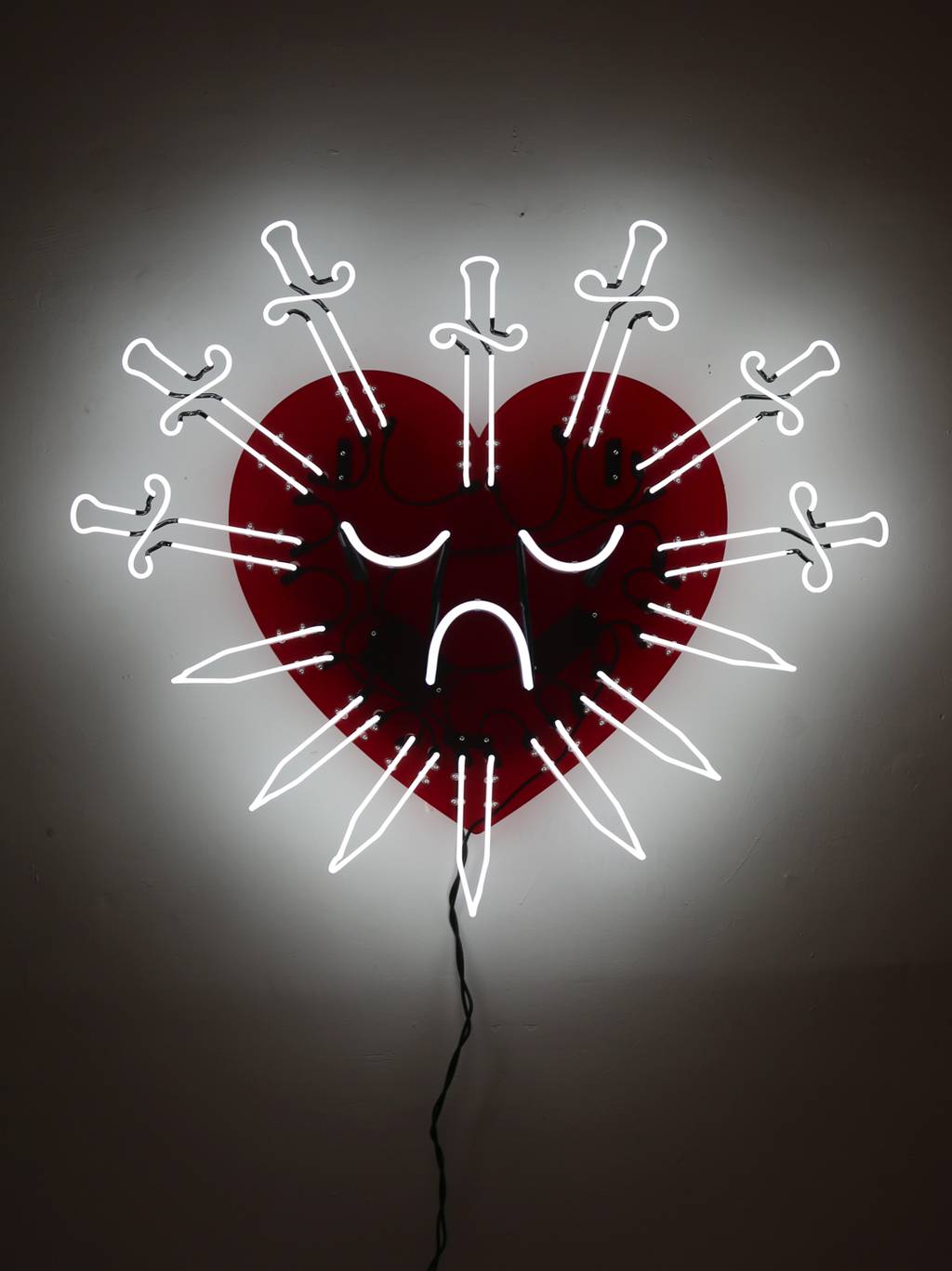 A neon sign featuring seven swords mounted to a transparent red acrylic piece cut in the shape of a heart. 