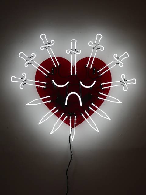 A neon sign featuring seven swords mounted to a transparent red acrylic piece cut in the shape of a heart. 